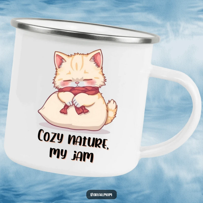 Funny Bobtail cat in a yarn scarf, kneading a cushion, on a durable camping mug.