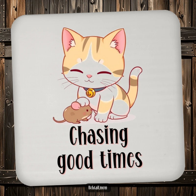 Funny Bobtail cat with a bell collar playfully nudging a toy mouse, featured on a protective, humorous drink coaster.