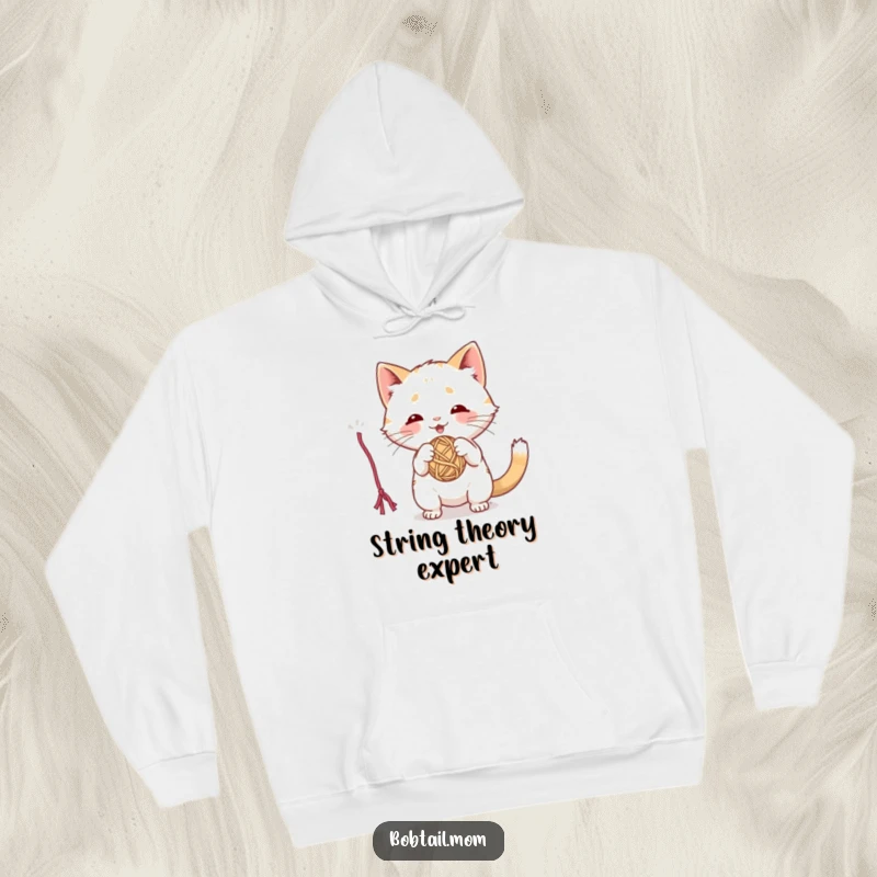 Funny hoodie featuring a playful Bobtail cat intensely batting at a dangling yarn ball, mid-pounce.