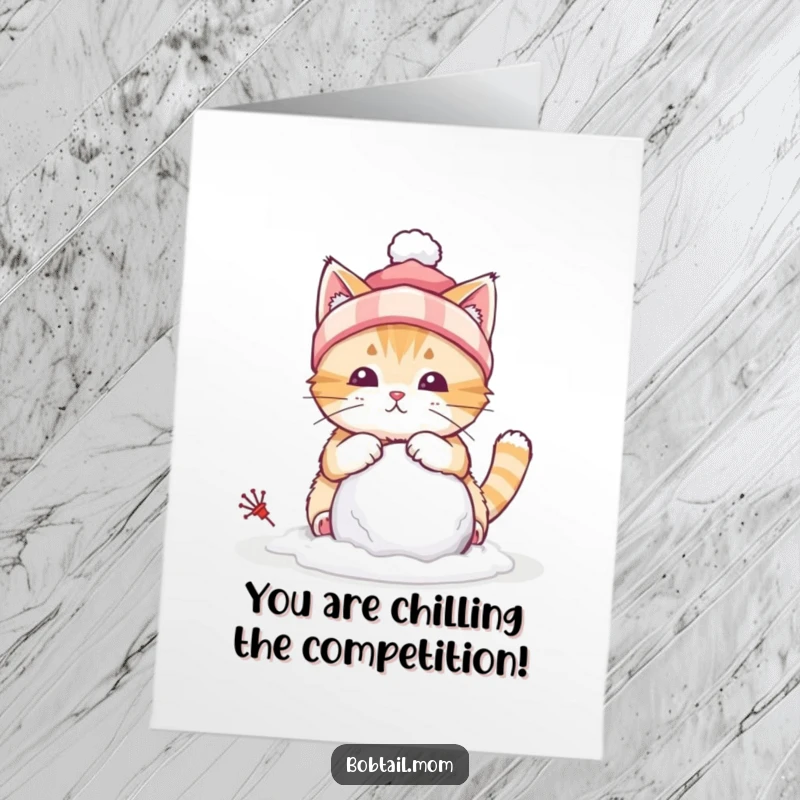 Funny Free Printable congratulations card of a bobtail cat wearing a winter hat, focused on building a tiny snowball.